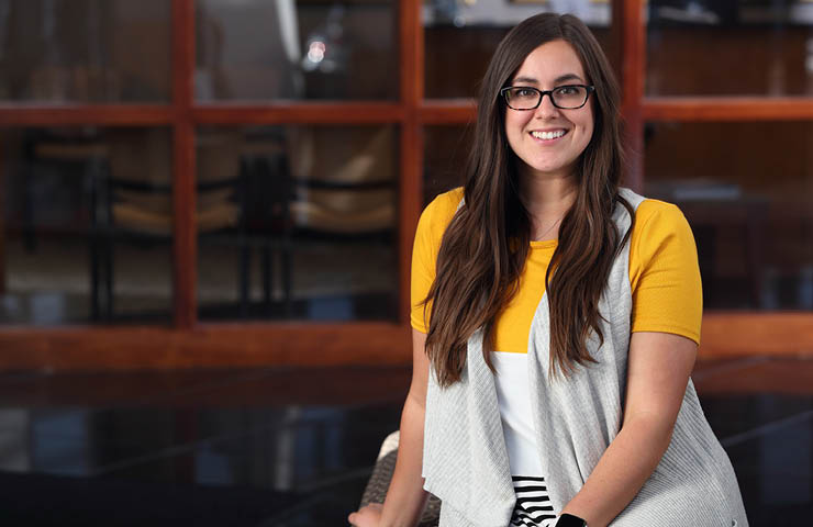 M.Ed. student in a yellow shirt sits in the Cleveland Center Lobby.